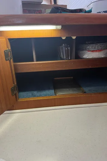 Half Fast Yacht Photos Pics Wooden cabinet interior on a 1992 Post 46 Sportfish boat, with shelves and stored items.