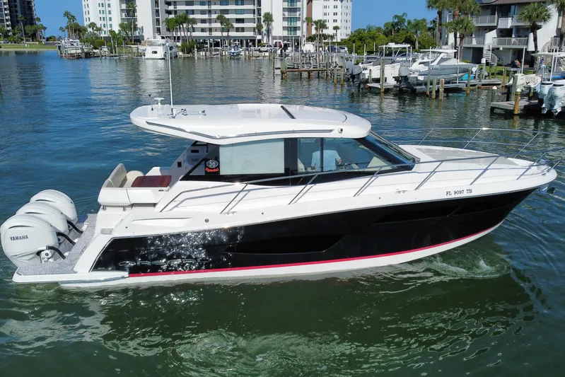  Yacht Photos Pics 2022 Regal 38 XO boat cruising in a marina with modern buildings in the background.