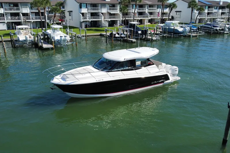  Yacht Photos Pics 2022 Regal 38 XO boat cruising in a marina with waterfront condos in the background.