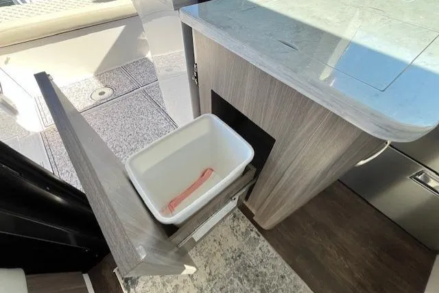  Yacht Photos Pics 2022 Regal 38 XO yacht interior with pull-out trash bin in modern kitchen area.