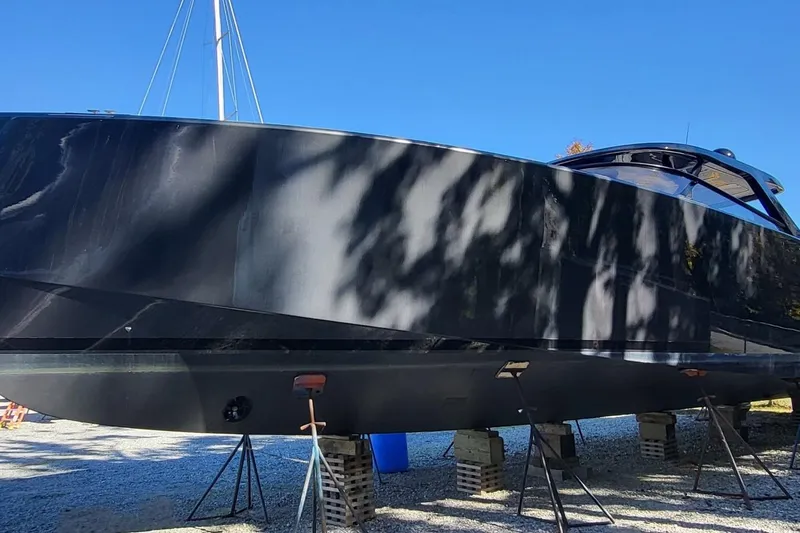  Yacht Photos Pics 2023 VanDutch 56 yacht on stands, sleek black hull, under clear blue sky.
