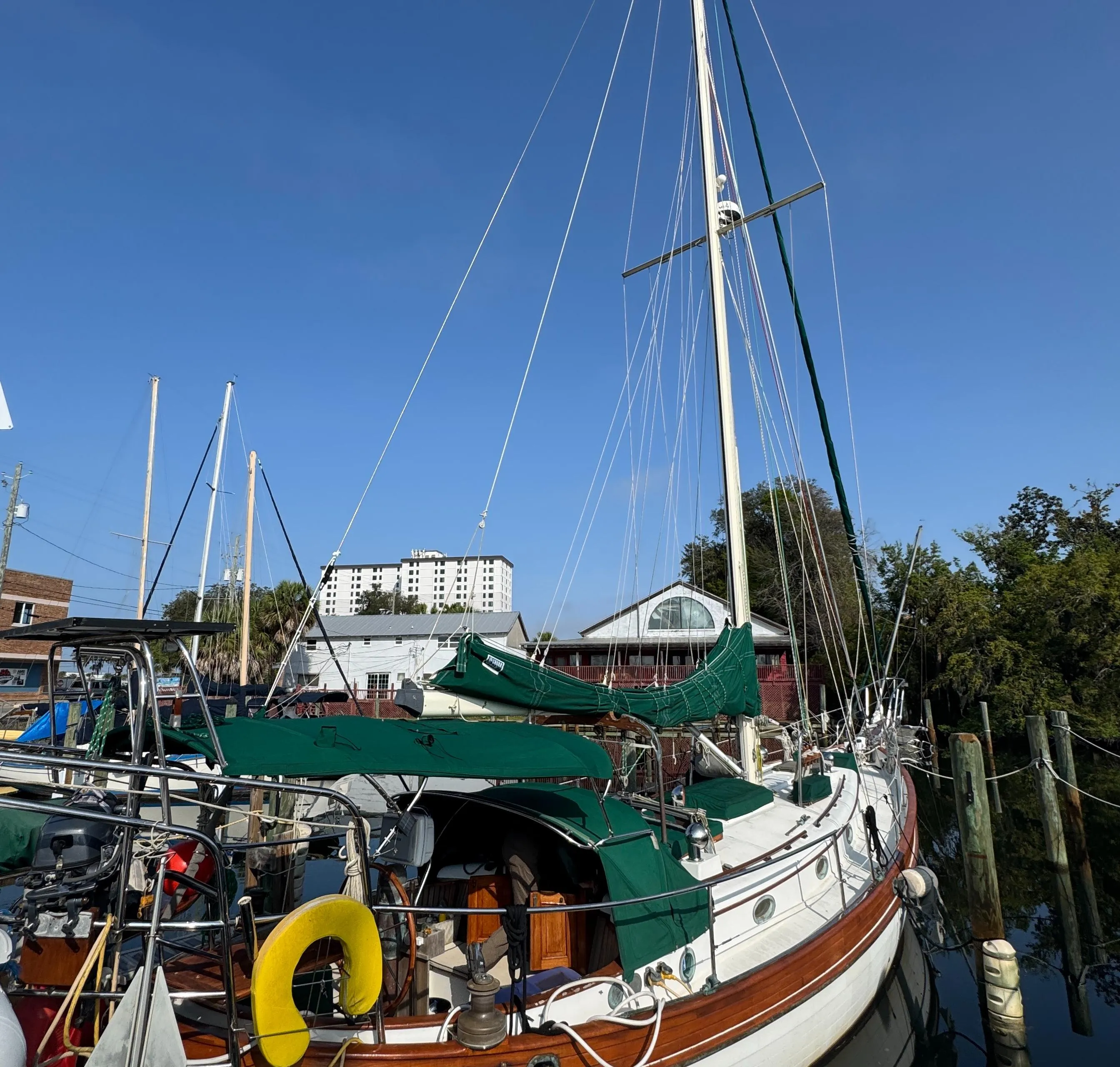 Sailboat Hans Christian 43T, 1989 model, docked with green covers and clear blue sky.