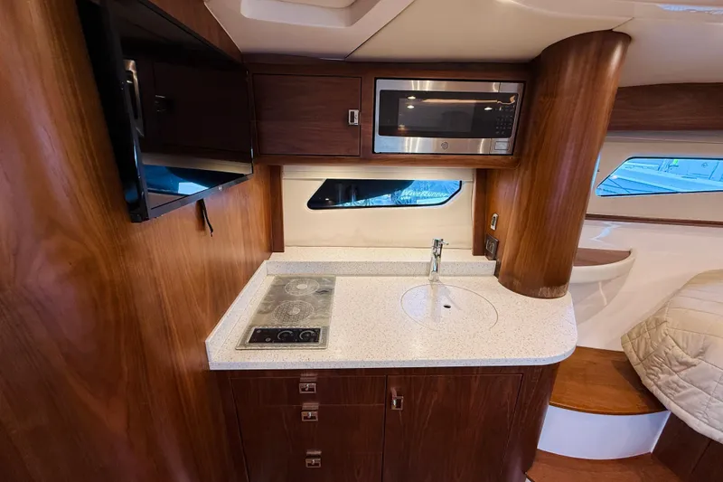  Yacht Photos Pics Luxurious 2021 Intrepid 410 Evolution yacht interior with modern kitchenette and wood finish.