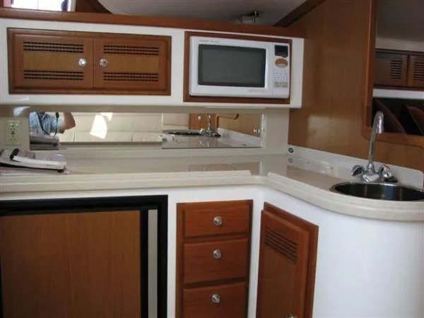  Yacht Photos Pics 2001 Cabo 35 Express yacht kitchen with microwave, sink, and wooden cabinetry.