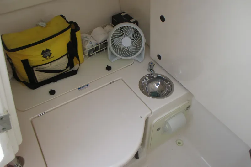  Yacht Photos Pics 2013 Pursuit ST 310 Sport cabin with sink, fan, and storage bag.