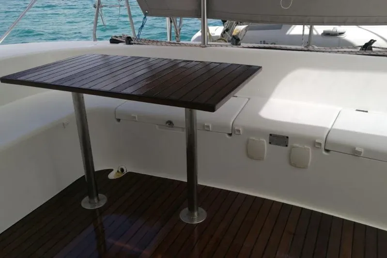 Sillage Yacht Photos Pics Lagoon 380 catamaran deck with wooden table, 2002 model, overlooking the ocean.
