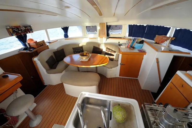 Sillage Yacht Photos Pics Interior of a 2002 Lagoon 380 catamaran with cozy seating and wooden accents.