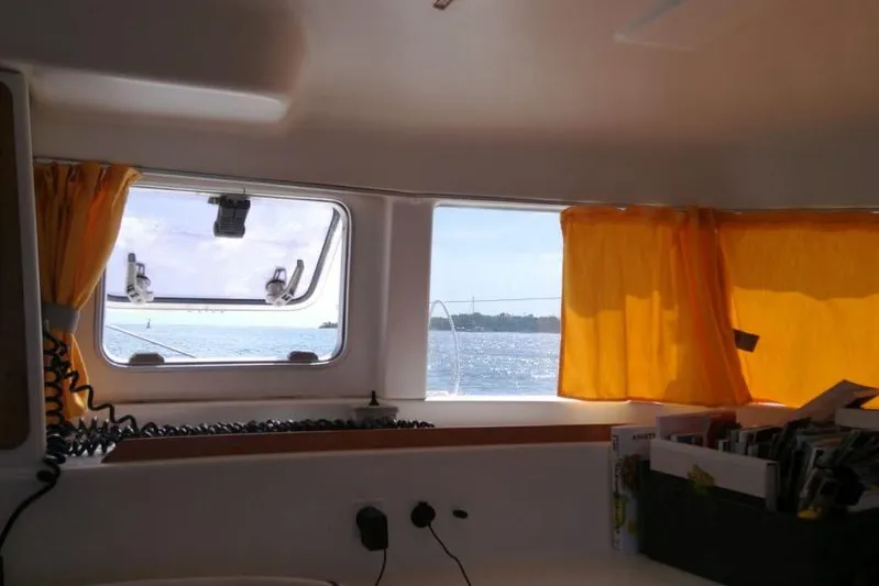 Sillage Yacht Photos Pics Interior view from a 2002 Lagoon 380 catamaran, showcasing windows with yellow curtains.