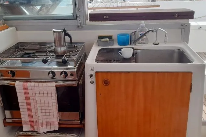 Sillage Yacht Photos Pics Compact kitchen area on a 2002 Lagoon 380 catamaran with stove and sink.
