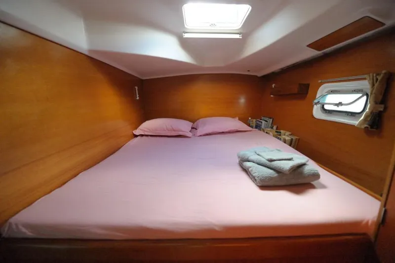 Sillage Yacht Photos Pics Cozy cabin interior of 2002 Lagoon 380 catamaran with pink bedding and porthole window.