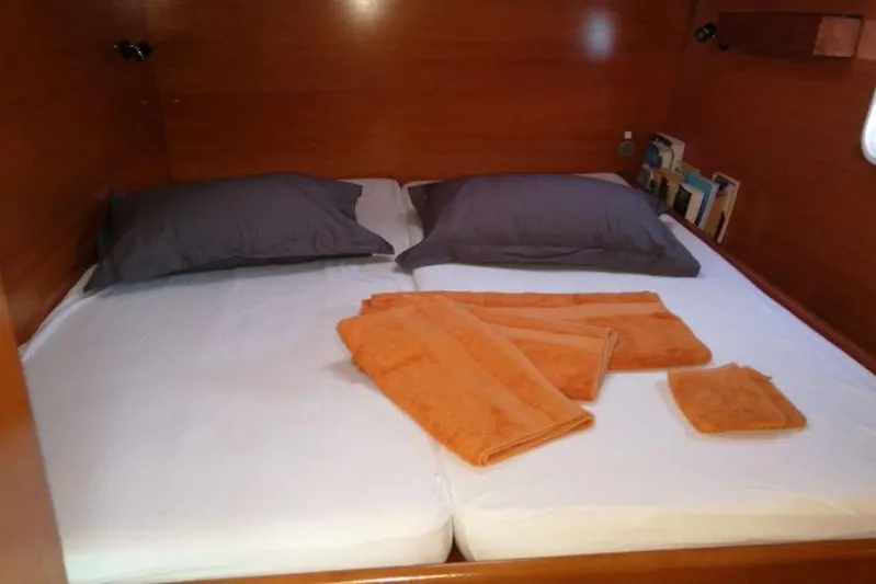 Sillage Yacht Photos Pics Cozy cabin bed in 2002 Lagoon 380 catamaran with orange towels and gray pillows.