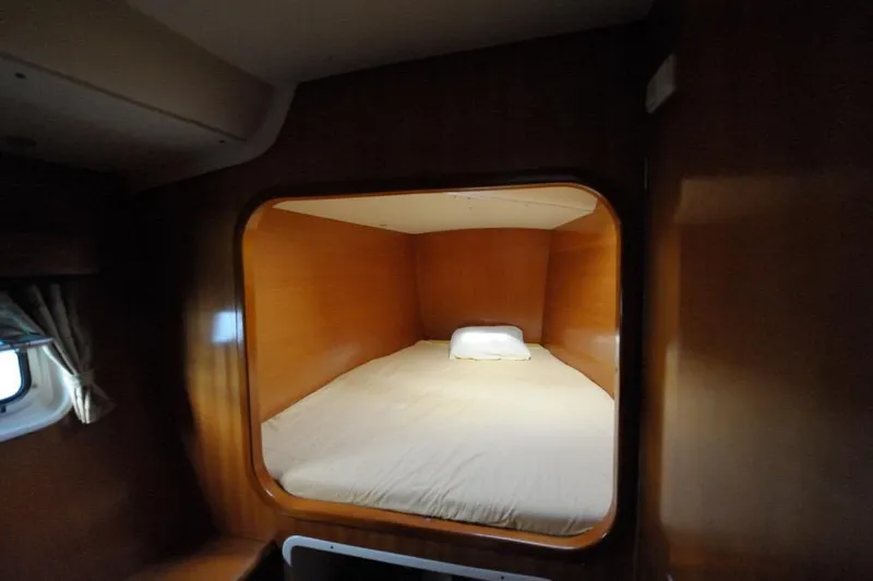 Sillage Yacht Photos Pics Cozy cabin bed inside a 2002 Lagoon 380 catamaran, featuring wooden interior and a small window.