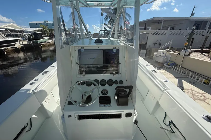  Yacht Photos Pics 2003 Contender 27 Open boat cockpit with Garmin navigation system, docked by waterfront homes.