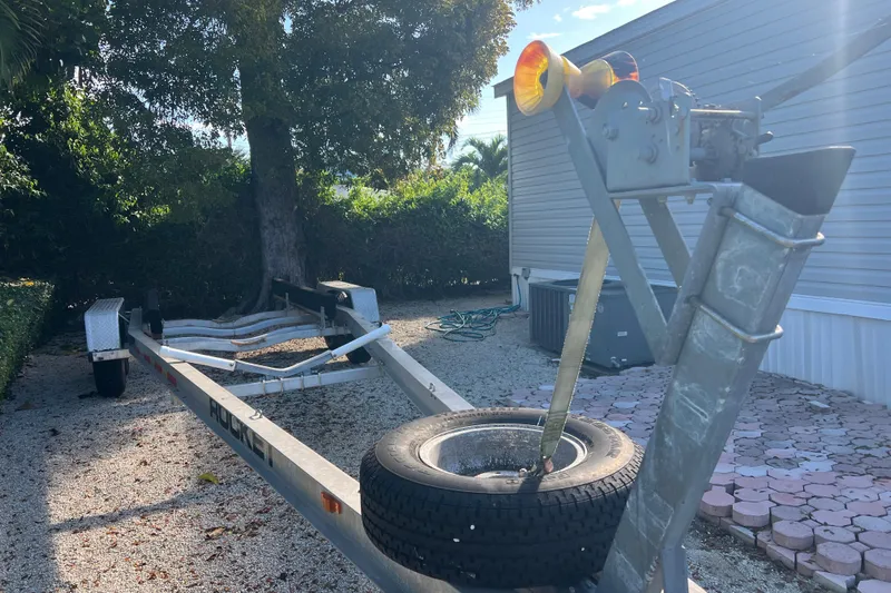  Yacht Photos Pics Boat trailer for 2003 Contender 27 Open, parked outdoors on gravel driveway.