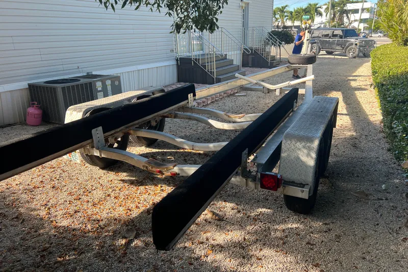  Yacht Photos Pics Boat trailer for 2003 Contender 27 Open, parked on gravel near a building.