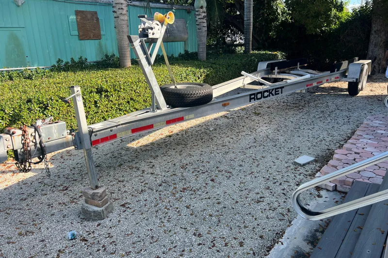  Yacht Photos Pics Boat trailer for 2003 Contender 27 Open, parked on gravel with greenery background.