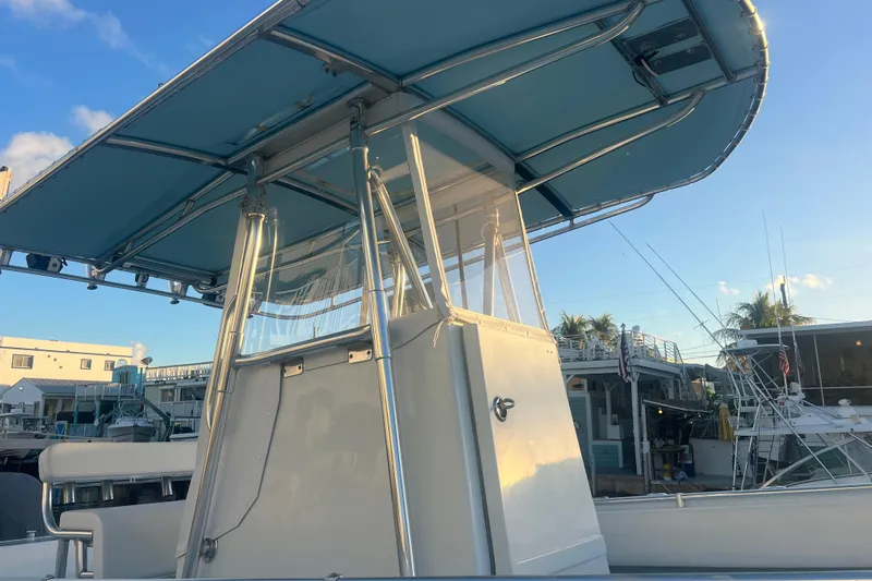  Yacht Photos Pics 2003 Contender 27 Open boat with blue canopy, docked under clear sky.