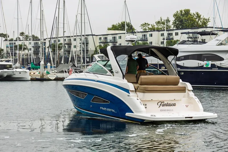 Fantasea Yacht Photos Pics 2014 Regal 32 Express boat in marina, with people onboard, surrounded by sailboats.