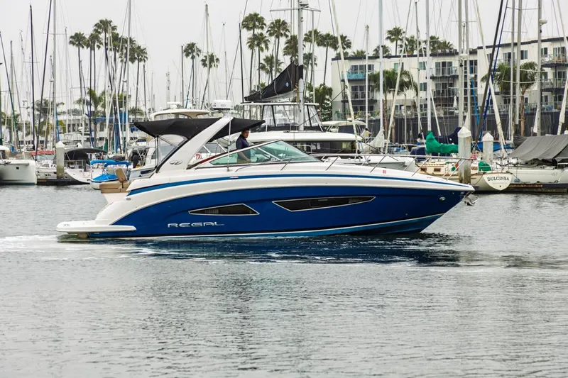 Fantasea Yacht Photos Pics 2014 Regal 32 Express boat cruising in a marina with sailboats in the background.