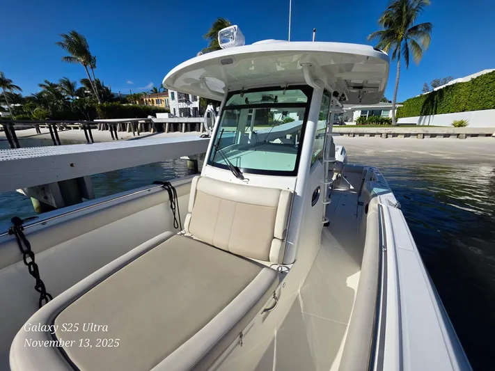  Yacht Photos Pics Boston Whaler 330 Outrage 2022 docked by a sunny waterfront with palm trees.