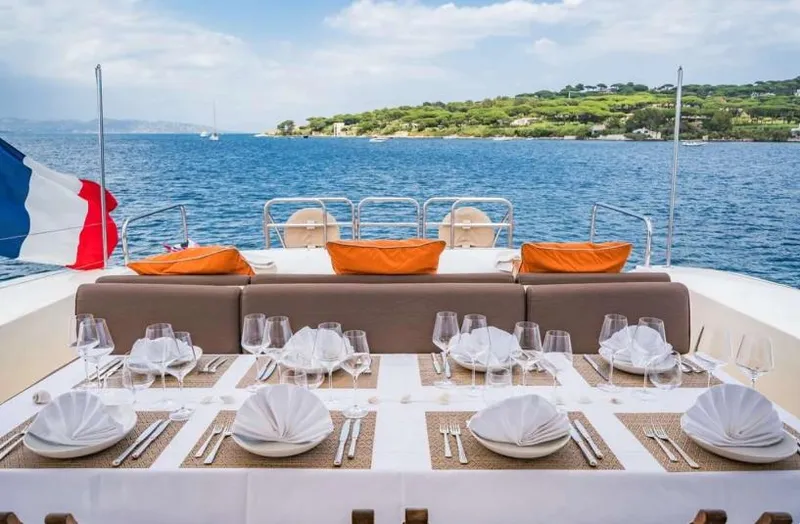 Eclat Yacht Photos Pics Luxurious dining setup on 2008 Arno Leopard 31 yacht, overlooking serene ocean and coastal landscape.