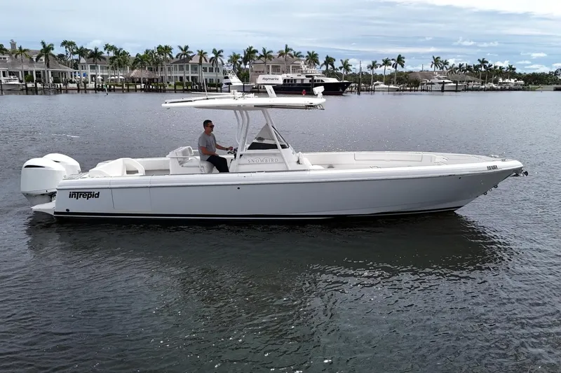 Yacht Photos Pics 2011 Intrepid 323 Cuddy boat on water, with palm trees and houses in background.