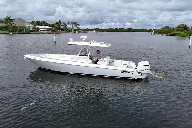  Yacht Photos Pics 2011 Intrepid 323 Cuddy boat cruising on a calm waterway under cloudy skies.