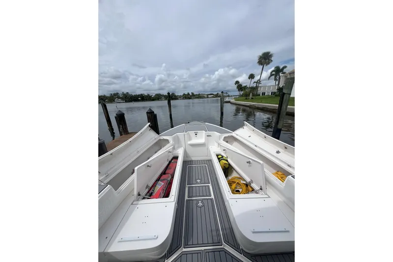  Yacht Photos Pics 2011 Intrepid 323 Cuddy boat with open storage compartments, docked by a scenic waterfront.