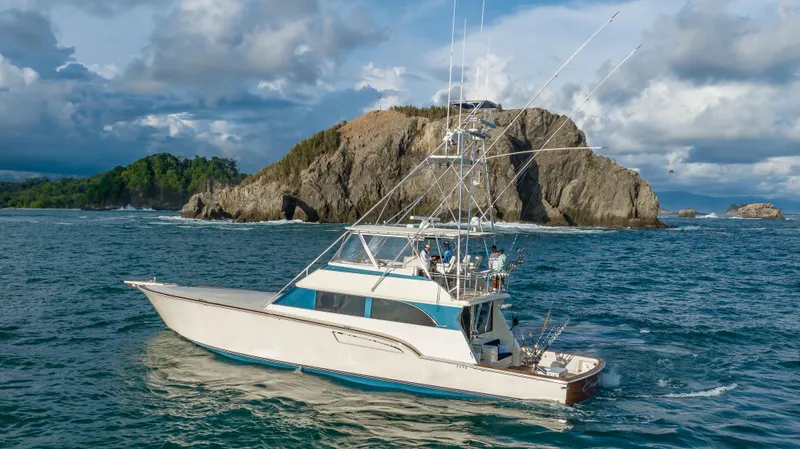 Crushing It Yacht Photos Pics 1996 Donzi 72 Custom Convertible yacht cruising near rocky island.