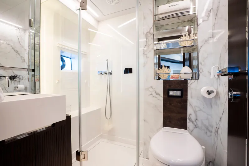 Masie Yacht Photos Pics Luxurious yacht bathroom with marble walls, modern fixtures, and glass shower in Pearl 62, 2023 model.