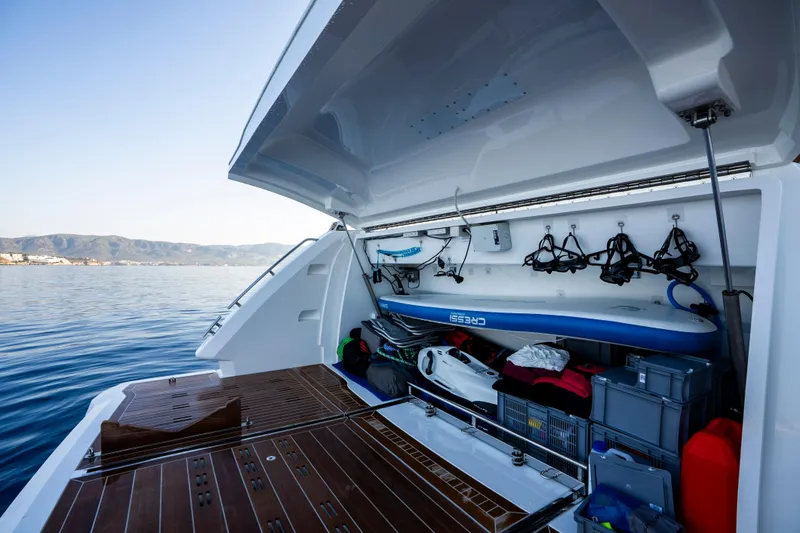 Masie Yacht Photos Pics 2023 Pearl 62 yacht with open storage, paddleboard, and equipment, docked on calm water.