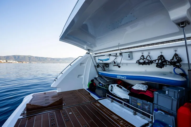 Masie Yacht Photos Pics 2023 Pearl 62 yacht with open storage compartment, paddleboard, and scenic ocean view.