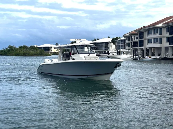  Yacht Photos Pics 2024 Pursuit 358 SPORT boat cruising near waterfront homes under cloudy skies.