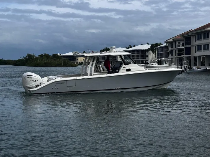  Yacht Photos Pics 2024 Pursuit 358 SPORT boat cruising on a calm waterway near residential buildings.