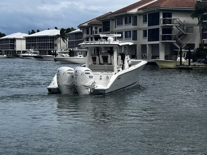  Yacht Photos Pics 2024 Pursuit 358 SPORT boat with twin Yamaha engines on a calm waterfront.