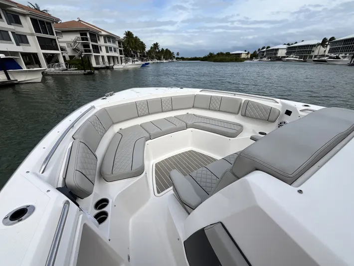  Yacht Photos Pics 2024 Pursuit 358 SPORT boat with spacious seating, docked near waterfront homes.