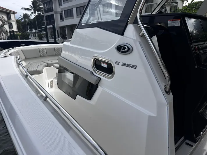  Yacht Photos Pics 2024 Pursuit 358 SPORT boat, sleek design, luxury seating, docked near waterfront buildings.