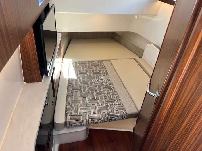 Yacht Photos Pics 2024 Pursuit 358 SPORT cabin interior with bed and TV, featuring wood accents.