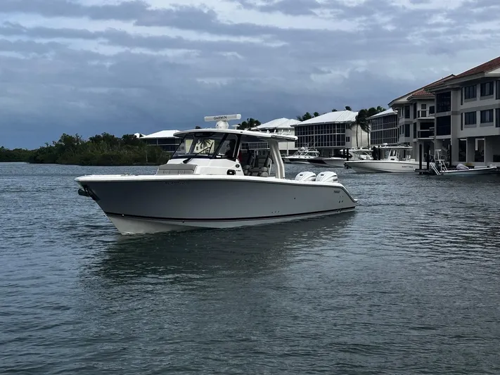  Yacht Photos Pics 2024 Pursuit 358 SPORT boat on water near waterfront homes under cloudy sky.