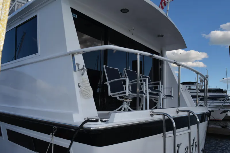 Lady Laura Yacht Photos Pics 1989 Viking Motor Yacht with deck chairs, docked under a blue sky.