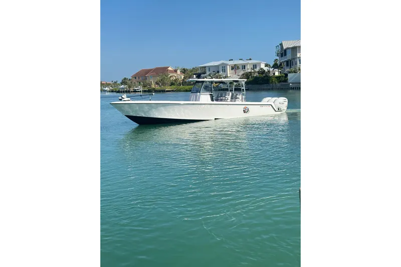  Yacht Photos Pics 2025 Contender 39 ST boat on calm water near waterfront homes.