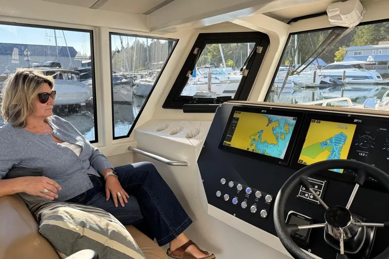  Yacht Photos Pics Woman relaxing inside 2025 Custom JR Marine 33 Savage boat, with navigation screens visible.