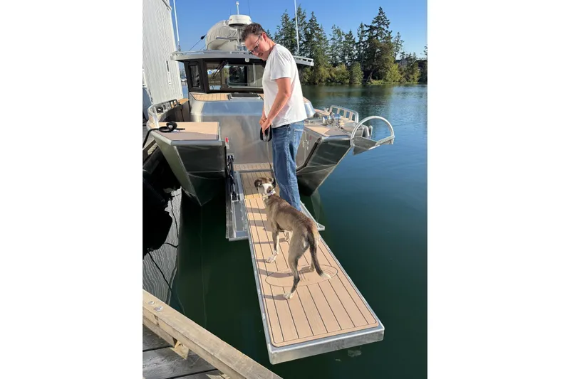  Yacht Photos Pics Man and dog on dock beside 2025 Custom JR Marine 33 Savage boat.