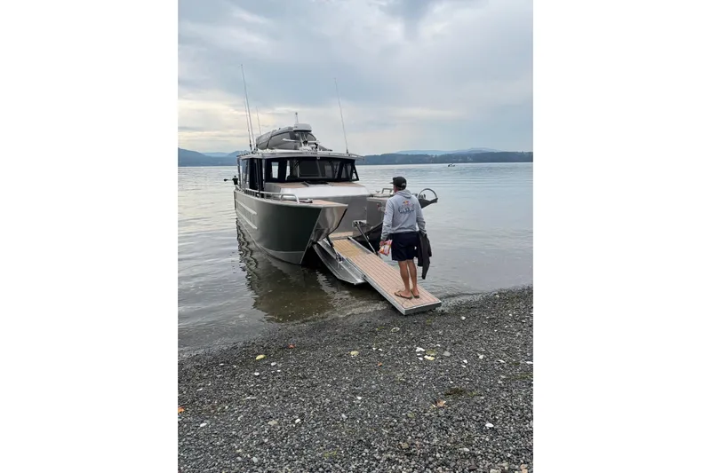  Yacht Photos Pics Man boarding 2025 JR Marine 33 Savage boat on a calm lake shore.
