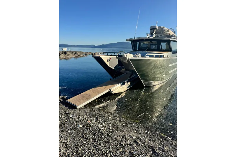 Yacht Photos Pics 2025 JR Marine 33 Savage boat with ramp on rocky shore, clear blue sky.