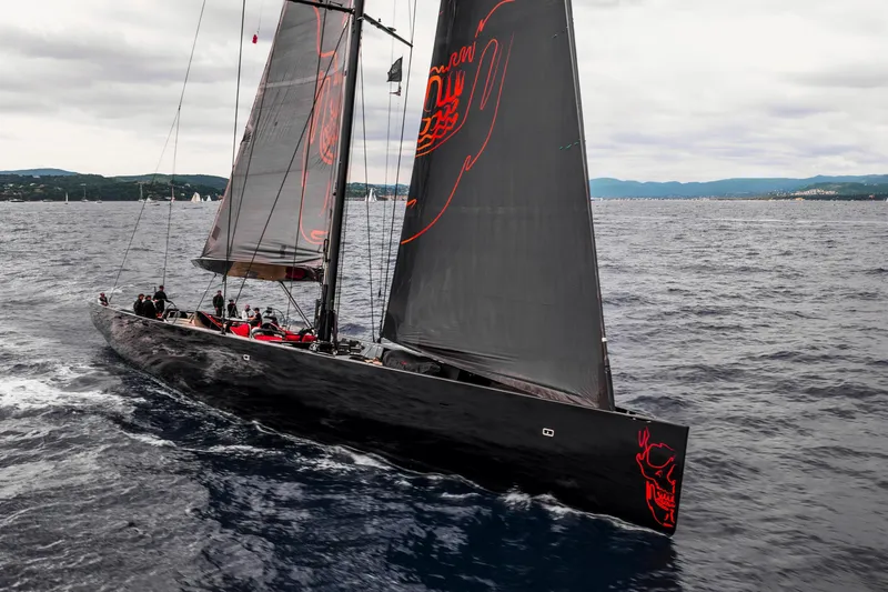 Black Sails Yacht Photos Pics Sleek 2009 Wally 130 yacht sailing on open sea with dark sails and red accents.