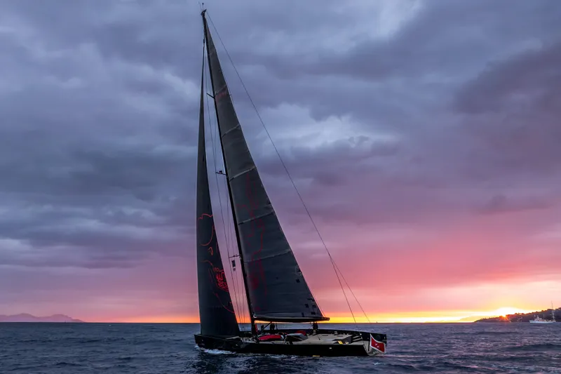 Black Sails Yacht Photos Pics Sailing yacht Wally 130, 2009 model, at sunset with dramatic sky and ocean backdrop.