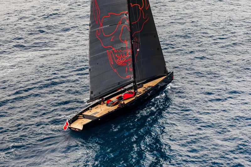 Black Sails Yacht Photos Pics Sleek 2009 Wally 130 yacht with striking black sail and red skull design on open sea.