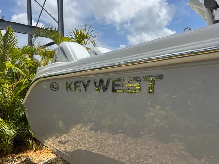  Yacht Photos Pics 2025 Key West 260 boat side view with logo, surrounded by tropical plants.