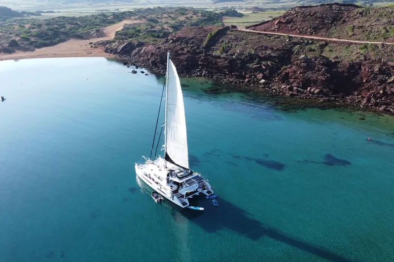 Audaz Yacht Photos Pics Sailing catamaran Privilege 615, 2007 model, anchored in clear turquoise waters near rocky coastline.
